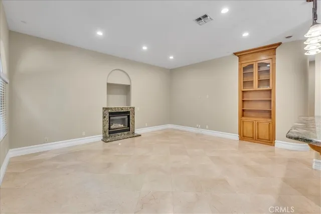 a view of an empty room with kitchen and window