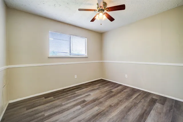 an empty room with a window and a fan