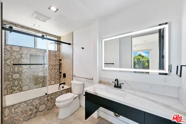 a bathroom with a granite countertop sink toilet a mirror and shower