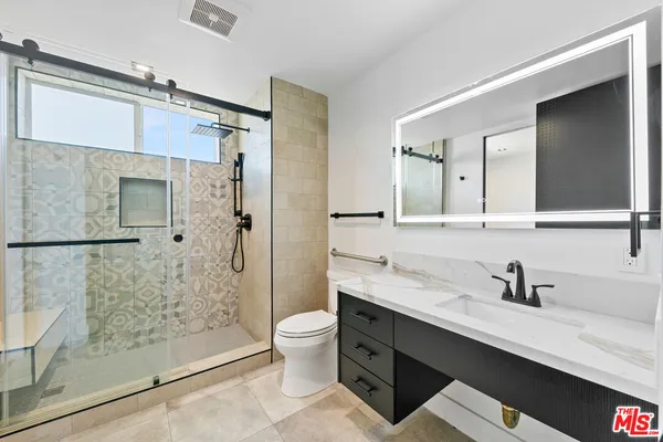 a bathroom with a double vanity sink toilet mirror and shower