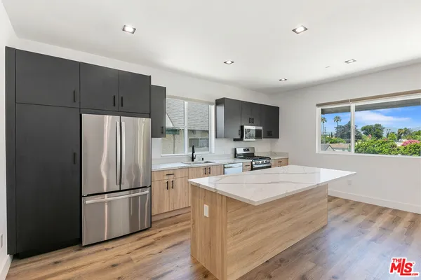 a kitchen with a refrigerator a sink wooden floor and cabinets