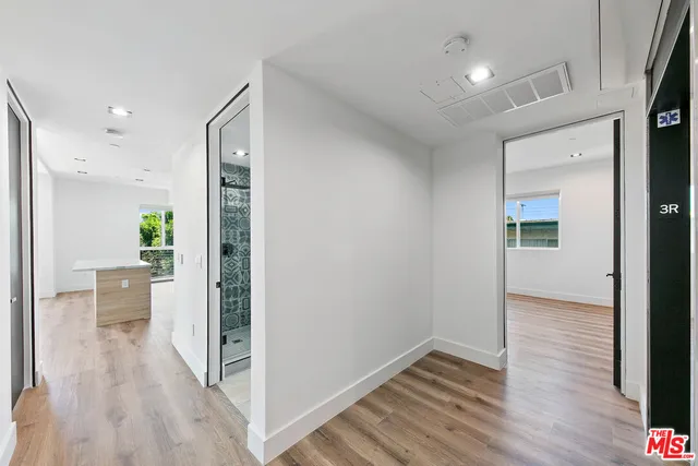 a view of a hallway with wooden floor and a bathroom