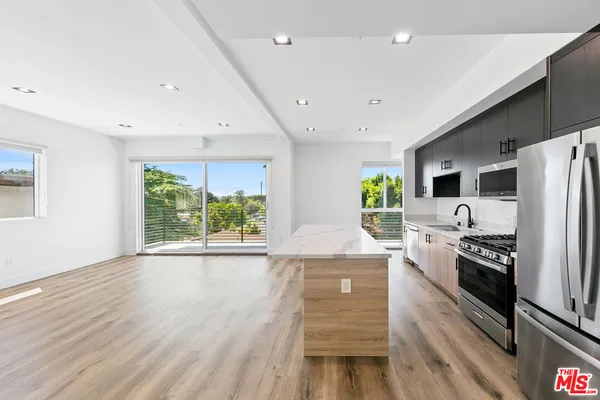 a kitchen with stainless steel appliances a stove top oven a refrigerator a sink and dishwasher with wooden floor