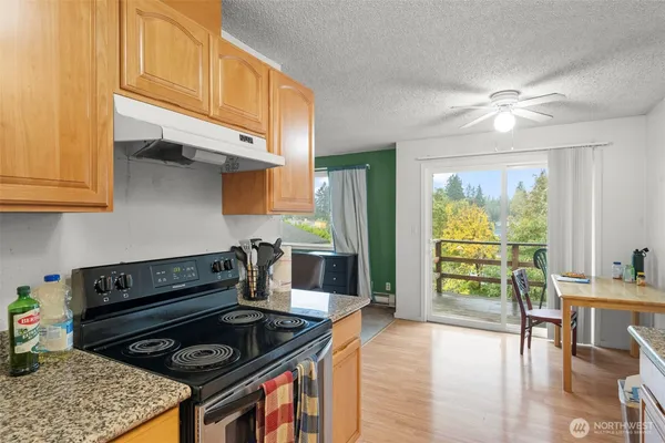 a kitchen with stainless steel appliances granite countertop a stove a refrigerator a sink a dining table and chairs with wooden floor