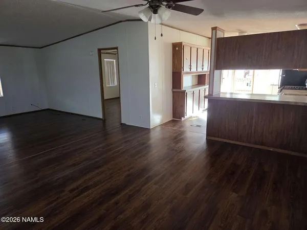 an empty room with wooden floor a ceiling fan and windows