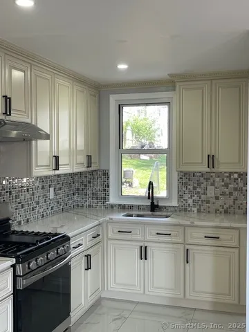 a kitchen with stainless steel appliances white cabinets and a stove top oven