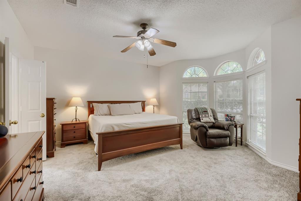 1413 West Peters Colony Road Carrollton, TX 75007 - Photo 17 of 29 a spacious bedroom with a bed and a chandelier