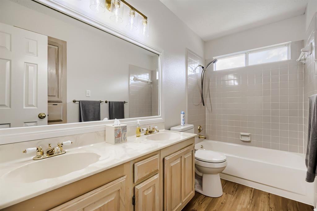 1413 West Peters Colony Road Carrollton, TX 75007 - Photo 25 of 29 a bathroom with a granite countertop sink toilet a large mirror a bathtub and shower