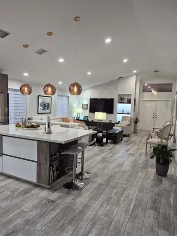 a living room with stainless steel appliances kitchen island granite countertop furniture and wooden floors
