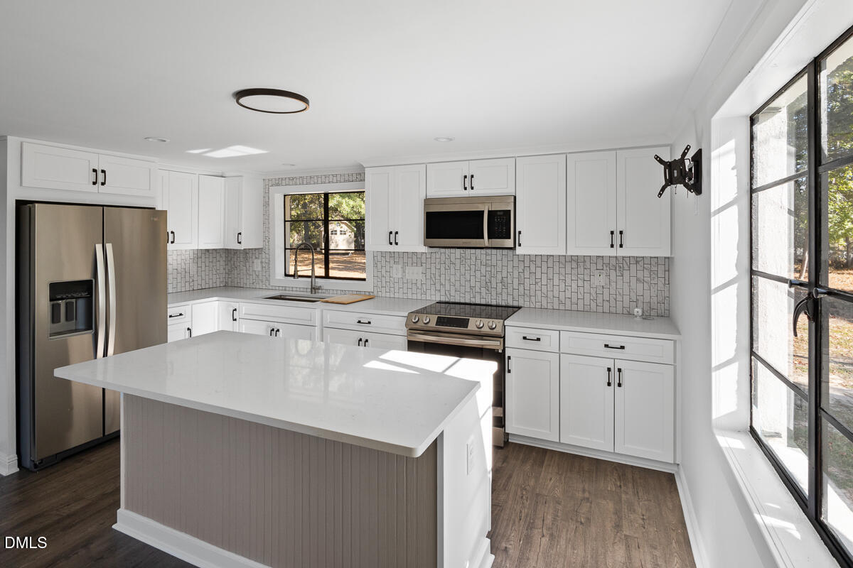 7700 Humie Olive Road Apex, NC 27502 - Photo 9 of 13 a kitchen with stainless steel appliances a sink stove refrigerator and a window