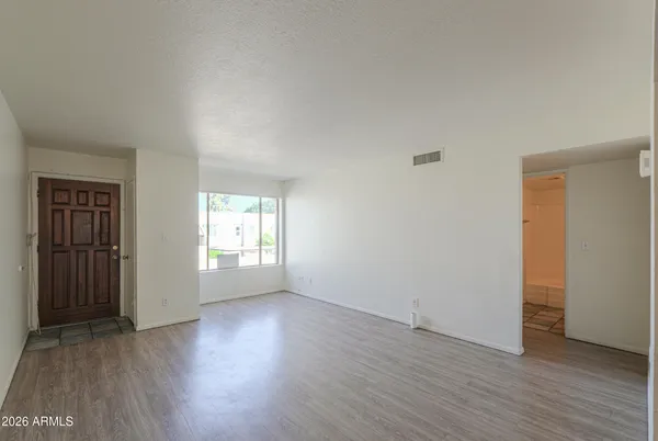 an empty room with wooden floor and windows