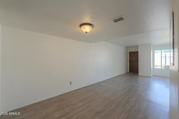 an empty room with wooden floor and windows