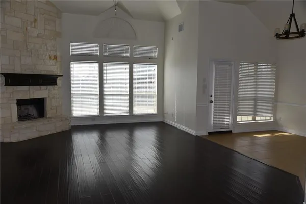 an empty room with wooden floor fireplace and windows