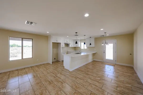 a large white kitchen with kitchen island a sink wooden floor and a refrigerator