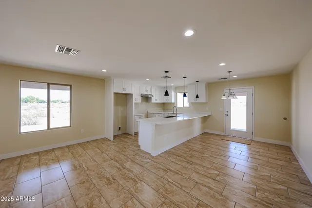 a large white kitchen with kitchen island a sink wooden floor and a refrigerator