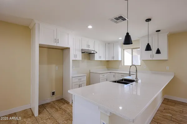 a kitchen with stainless steel appliances a sink a stove a refrigerator and white cabinets