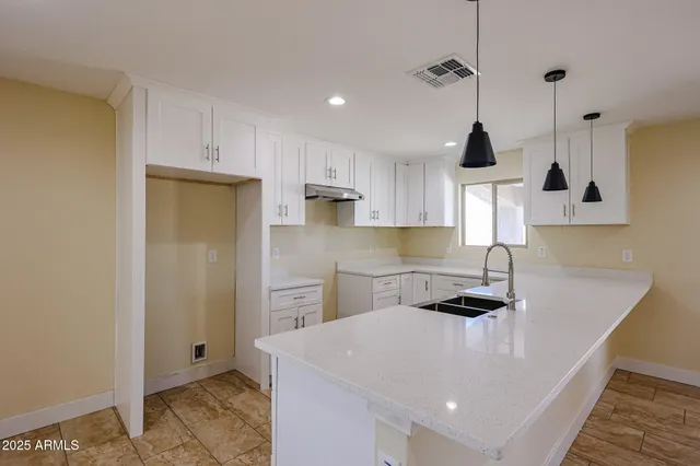 a kitchen with stainless steel appliances a sink a stove a refrigerator and white cabinets
