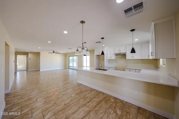 a large kitchen with stainless steel appliances a large counter top a stove and a wooden floors