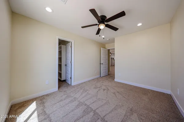 an empty room with a ceiling fan and carpet