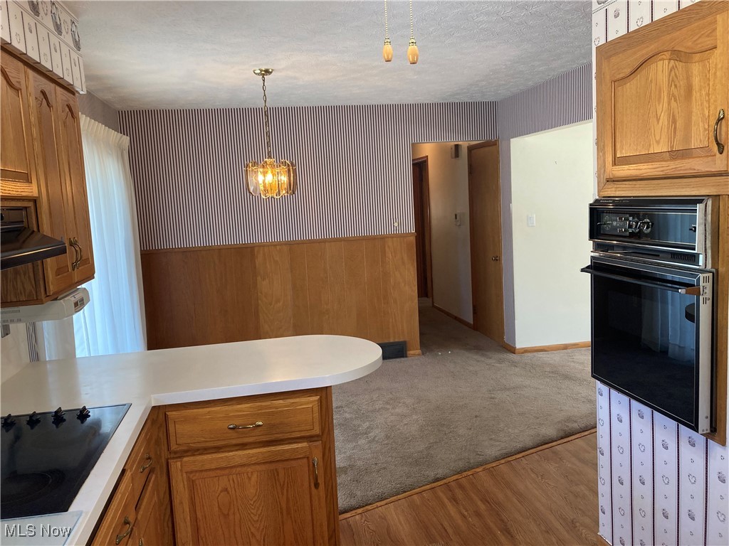 2547 Mayfair Road Akron, OH 44312 - Photo 11 of 50 Kitchen with hanging light fixtures, kitchen peninsula, a textured ceiling, black appliances, and light hardwood / wood-style flooring