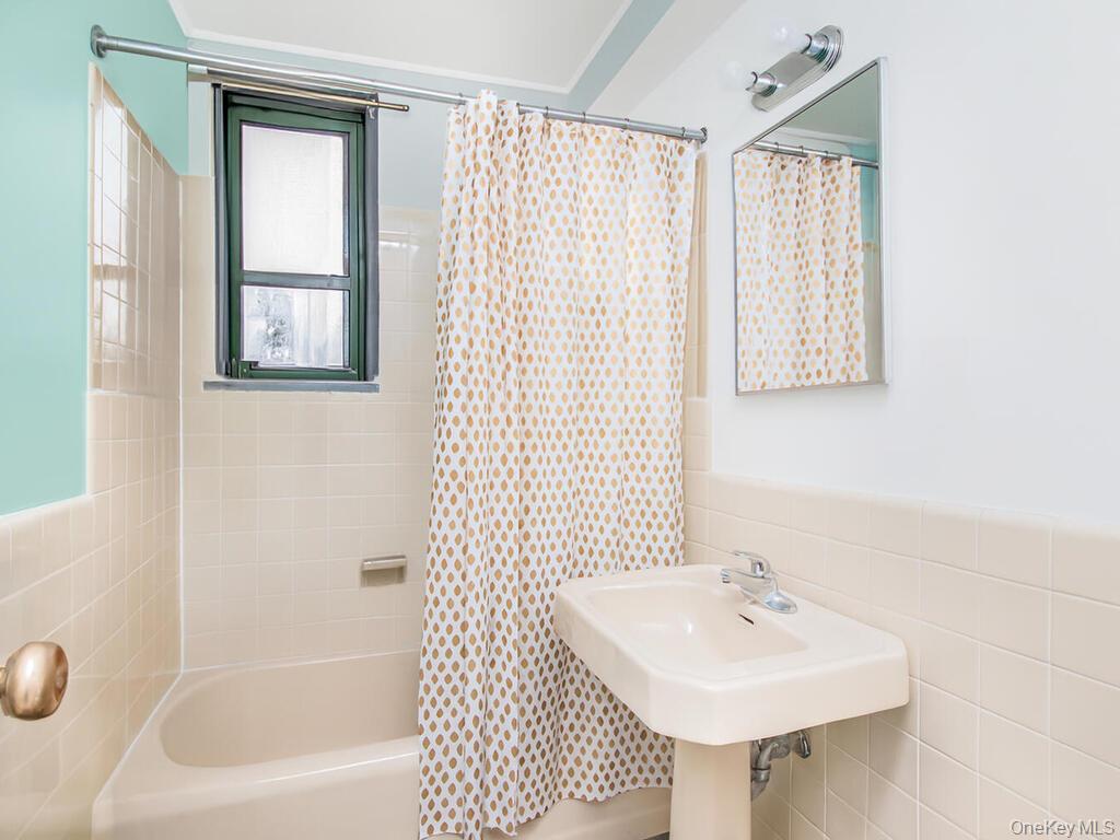 1521 Unionport Road, Unit 11A Bronx, NY 10462 - Photo 6 of 9 Bathroom with tile walls, shower / bath combination with curtain, and wainscoting