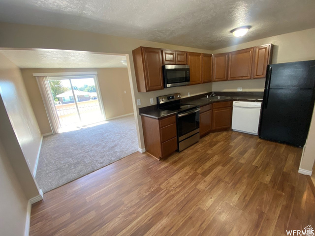 2182 West 5600th Street South Roy, UT 84067 - Photo 3 of 11 Kitchen featuring wood-finish flooring, dark countertops, and brown cabinetry