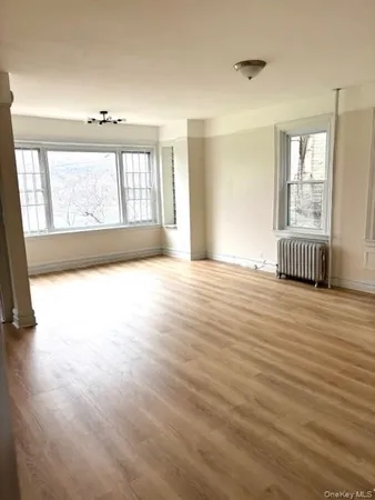 a view of an empty room with a window and wooden floor