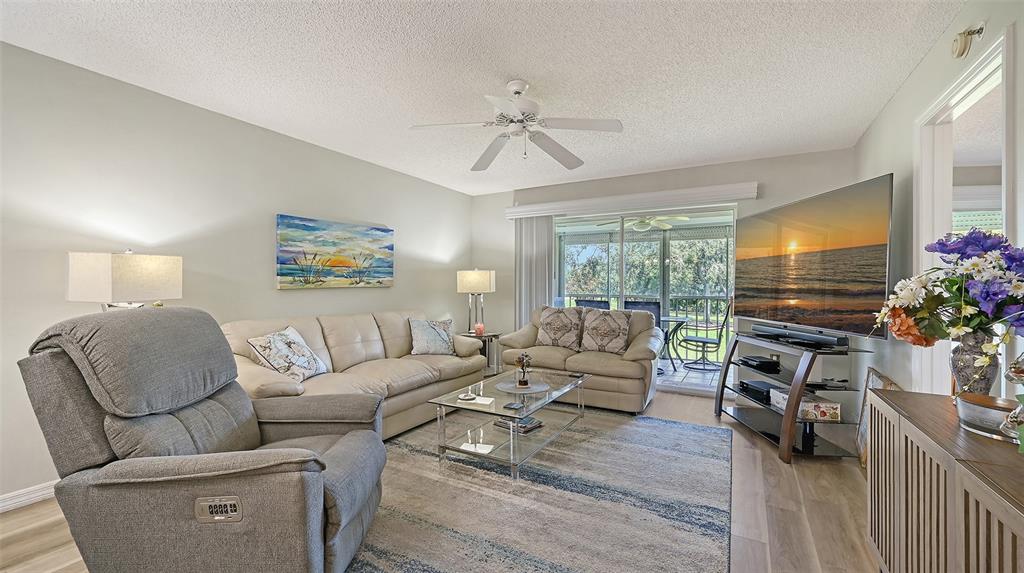 6505 Stone River Road, Unit 209 Bradenton, FL 34203 - Photo 11 of 47 a living room with furniture a flat screen tv and a floor to ceiling window