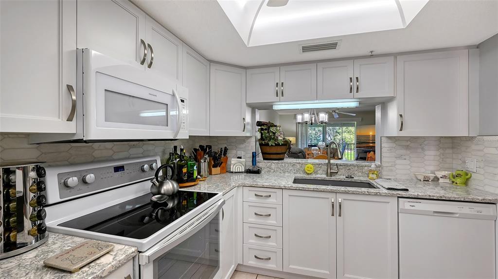 6505 Stone River Road, Unit 209 Bradenton, FL 34203 - Photo 6 of 47 a kitchen with white cabinets and appliances