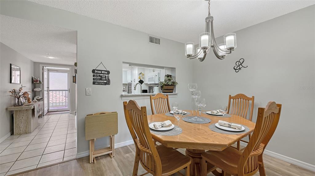 6505 Stone River Road, Unit 209 Bradenton, FL 34203 - Photo 9 of 47 a view of a dining room with furniture a chandelier and wooden floor