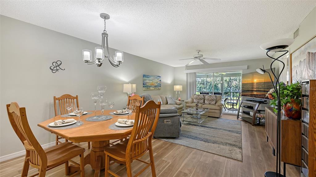 6505 Stone River Road, Unit 209 Bradenton, FL 34203 - Photo 10 of 47 a view of a dining room and livingroom with furniture wooden floor a chandelier