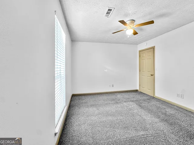 an empty room with a window and ceiling fan
