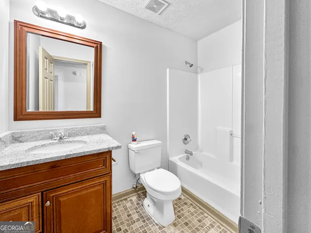 a bathroom with a granite countertop toilet sink and mirror