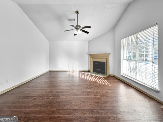 an empty room with windows and fireplace