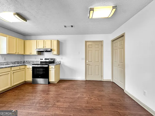 a kitchen with granite countertop a stove a sink and a window
