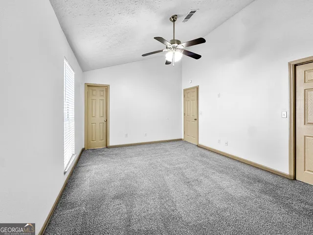 a view of an empty room with a chandelier fan