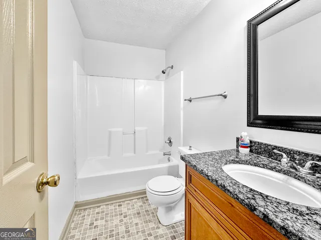 a bathroom with a granite countertop sink toilet a shower and a mirror