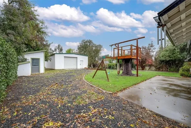 a view of a house with a yard and table and chairs under an umbrella