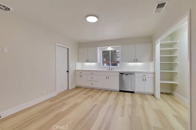 a large white kitchen with a sink dishwasher a stove and a refrigerator with wooden floor