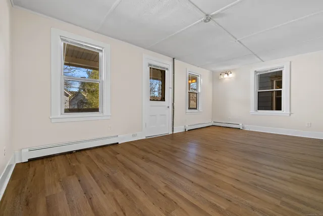 a view of an empty room with wooden floor and a window