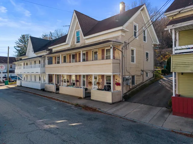 a view of a white building among the street with outdoor seating