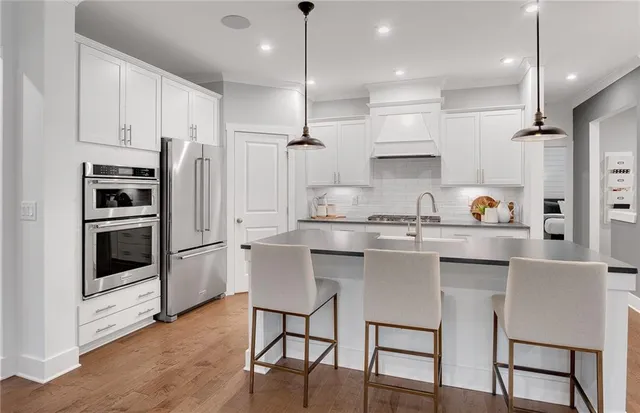 a kitchen with stainless steel appliances granite countertop a sink a stove a refrigerator and chairs