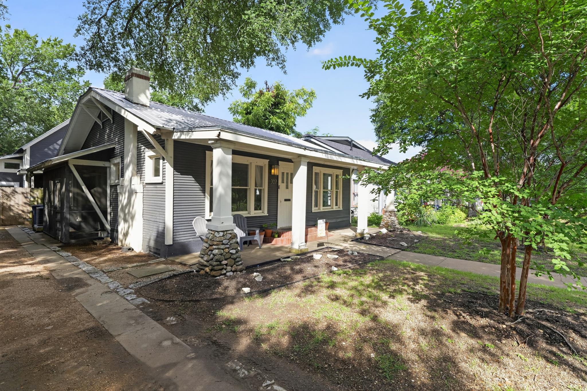 307 East 35th Street, Unit A Austin, TX 78705 - Photo 2 of 40 A classic bungalow facade, featuring a welcoming porch with stone pillars and a well-maintained, lush front yard.