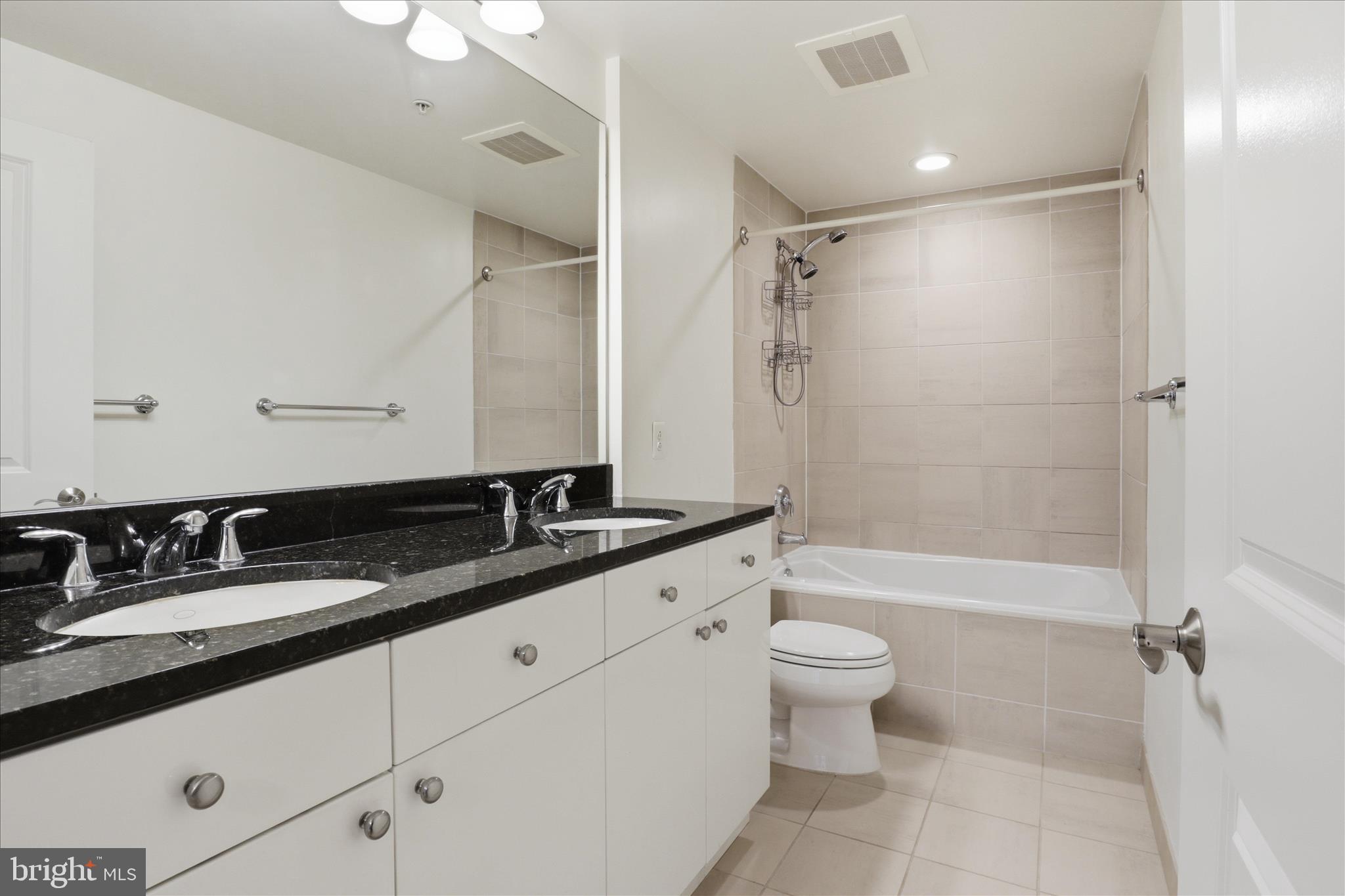 11990 Market Street, Unit 216 Reston, VA 20190 - Photo 31 of 41 a bathroom with a double vanity sink toilet mirror and shower