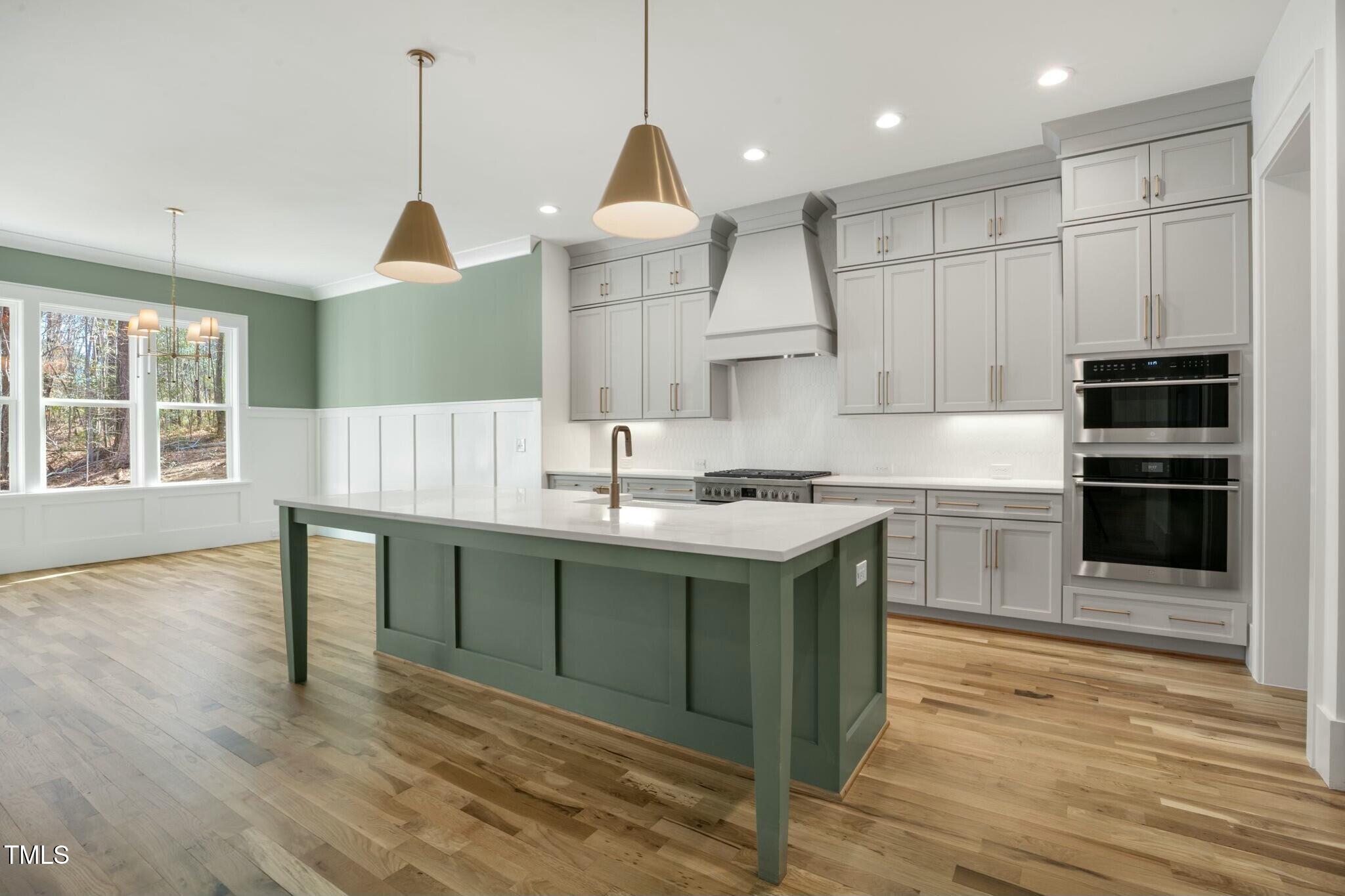 7112 Camp Side Court Raleigh, NC 27613 - Photo 8 of 39 a kitchen with kitchen island granite countertop a stove a sink a center island and wooden floor