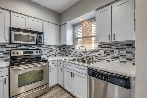 a kitchen with cabinets stainless steel appliances a sink and a stove