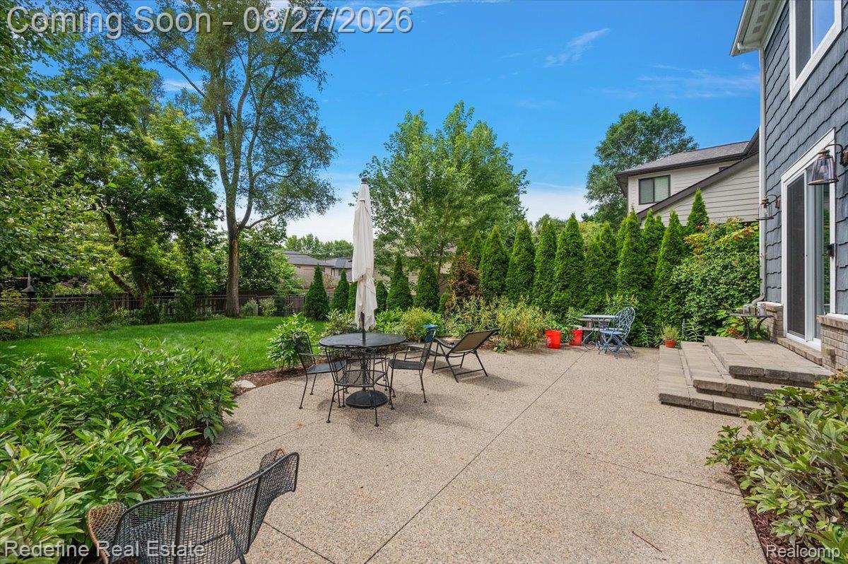 149 Woodward Avenue Rochester, MI 48307 - Photo 39 of 51 Expansive concrete patio with mature landscaping, including manicured lawn, established trees, and evergreen hedges