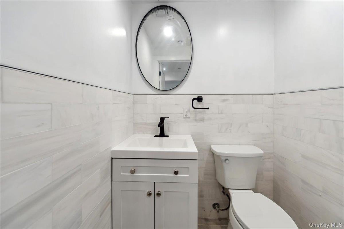 953 Tilden Street Bronx, NY 10469 - Photo 14 of 24 a bathroom with a sink a toilet and a mirror