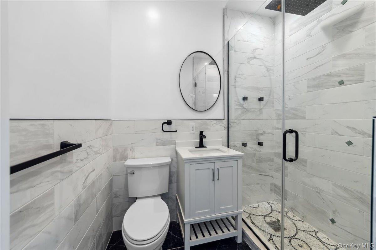 953 Tilden Street Bronx, NY 10469 - Photo 17 of 24 a bathroom with a toilet a sink and mirror