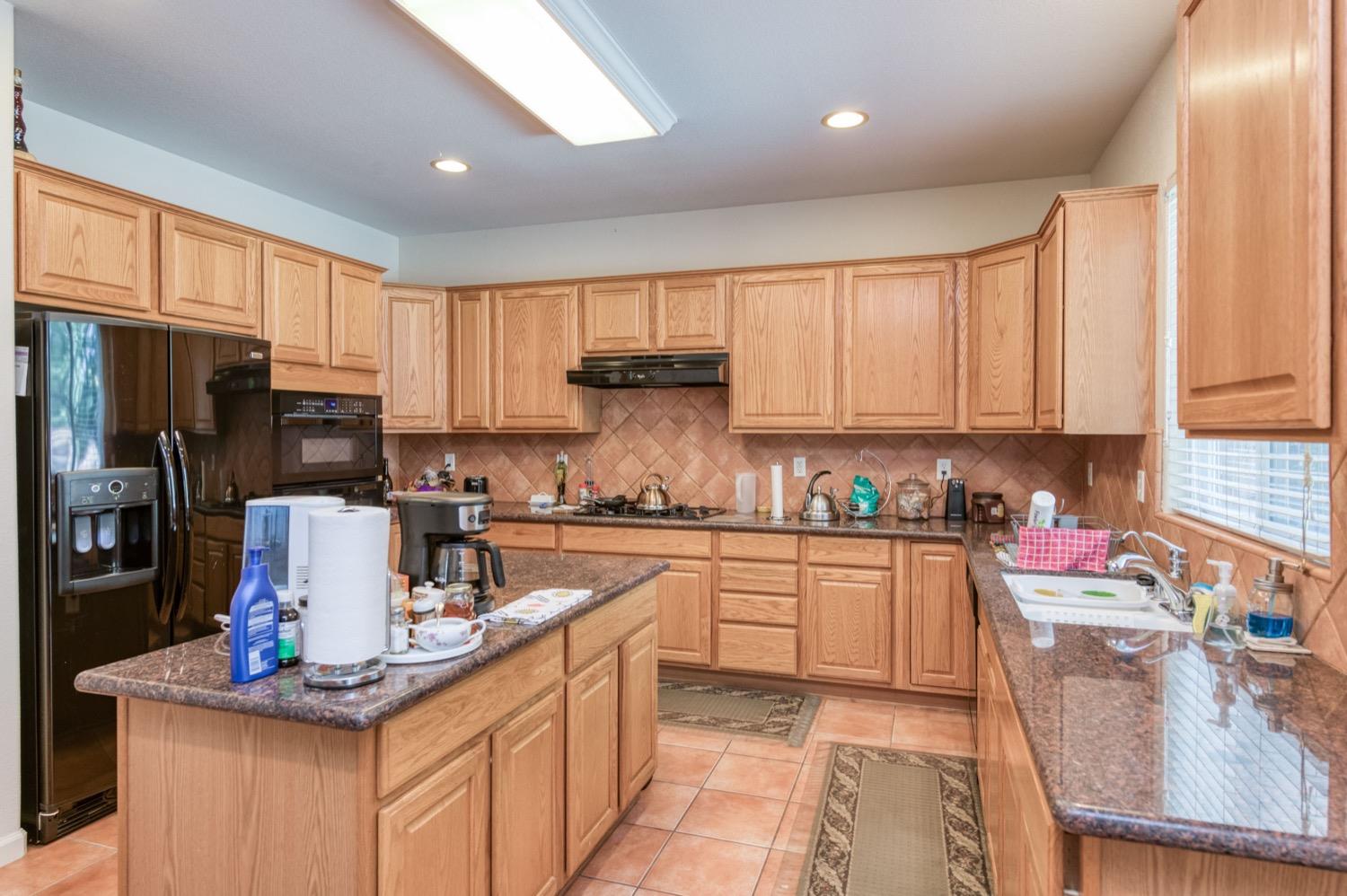 2661 Buckingham Avenue Clovis, CA 93611 - Photo 16 of 50 a kitchen with kitchen island granite countertop a sink cabinets and stainless steel appliances